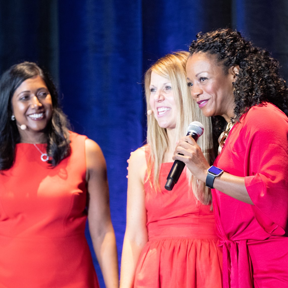 Three women talking on stage at an event. Three women talking on stage at an event.